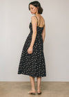 Woman wearing a black dress with white polka dots against a plain background