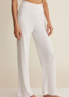 White ribbed pants worn by a person on a beige background