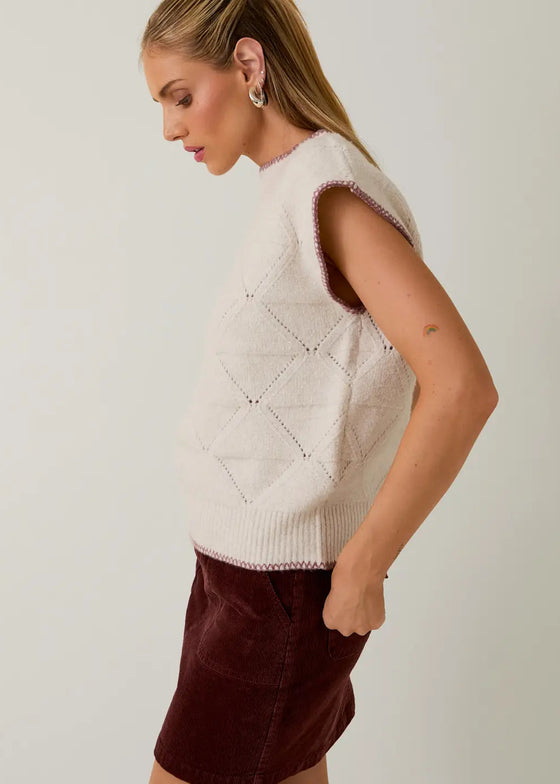 Woman wearing a beige knitted vest with a white background