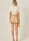 Woman wearing a beige top and skirt with a neutral background