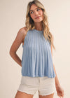 Woman wearing a light blue sleeveless top and white shorts on a beige background