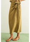 Person wearing a green wrap skirt with a plain background