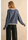 Person wearing a blue knitted sweater with a beige background