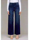 Person wearing dark blue wide-leg jeans and a white top on a neutral background