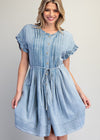 Woman wearing a light blue denim dress on a plain background