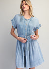 Woman wearing a light blue denim dress against a plain background