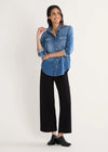 Woman wearing a blue denim shirt and black pants on a white background
