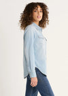 Woman wearing a light blue denim shirt and jeans on a white background
