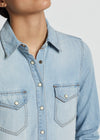 Light blue denim shirt worn by a person on a plain background