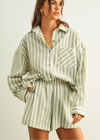Woman wearing a green and white striped outfit against a plain background