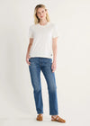 Woman wearing a white t-shirt and blue jeans on a plain background
