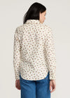 Woman wearing a floral patterned shirt and blue jeans on a plain background