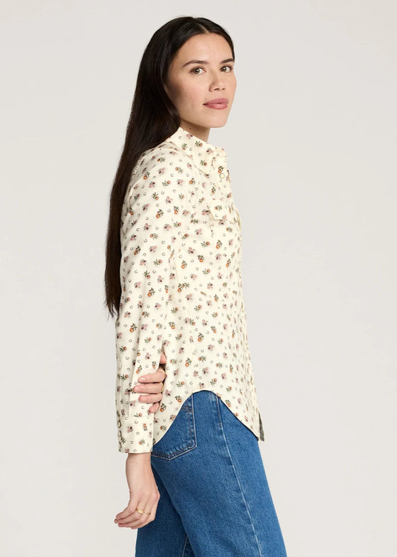 Woman wearing a floral blouse and blue jeans on a plain background