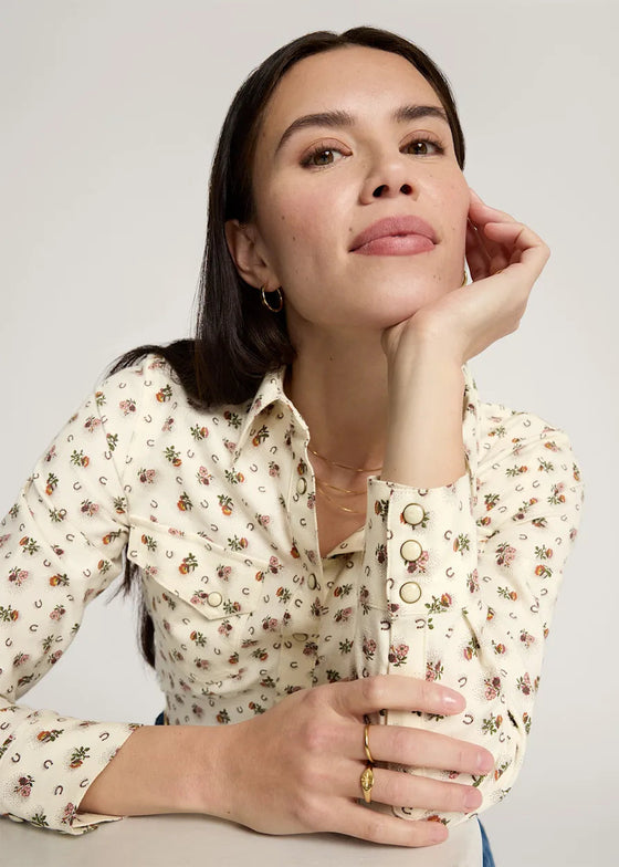 Woman wearing a floral blouse against a plain background