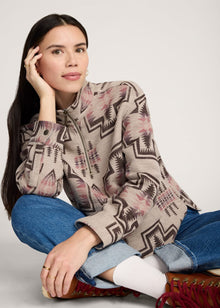  Woman wearing a patterned blouse and jeans sitting on a white background