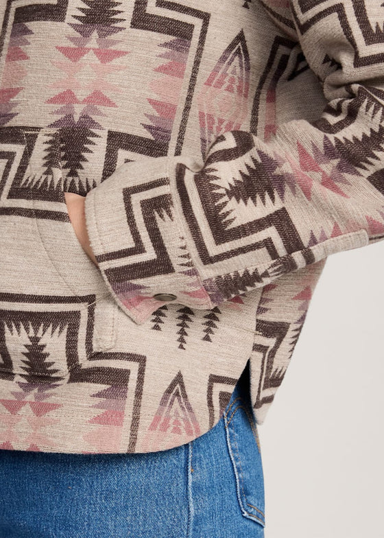 Close-up of a patterned shirt with geometric design and blue jeans.