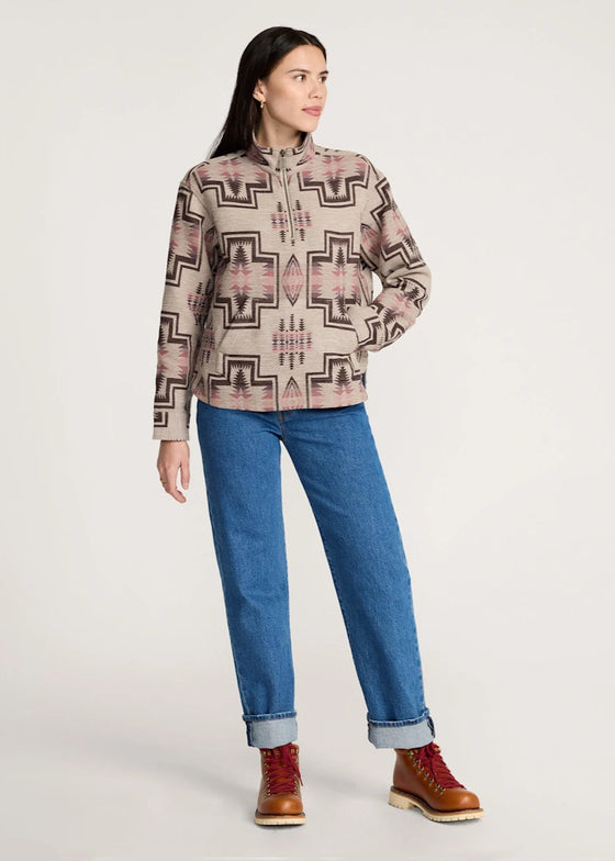 Woman wearing a patterned shirt, blue jeans, and brown boots on a white background