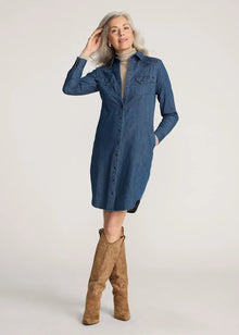  Woman wearing a blue denim dress and brown knee-high boots on a plain background