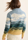 Person wearing a sweater with a landscape design on a plain background