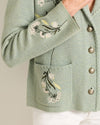 Green embroidered jacket with floral patterns on a plain background