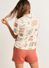 Person wearing a patterned shirt and shorts on a plain background