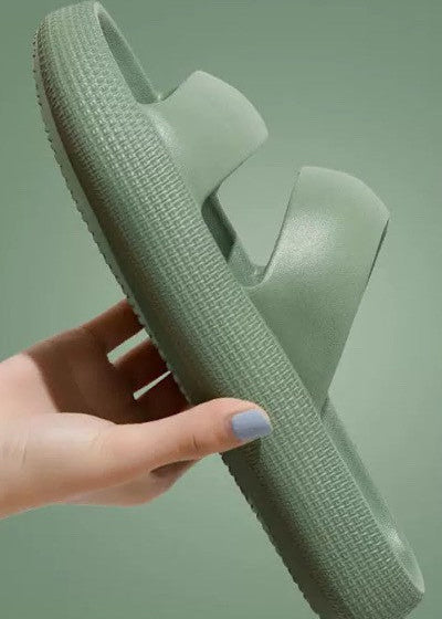 Green sandal held by a hand against a green background