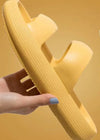 Yellow sandal held by a hand against a yellow background