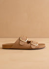 Tan sandal with gold buckle on a beige background