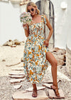 Woman in a floral dress holding flowers on a stone path.