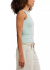 Woman wearing a light blue tank top and beige pants on a white background