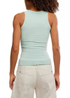 Person wearing a light green sleeveless top and beige pants on a white background