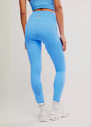 Person wearing blue leggings and a matching top on a plain background