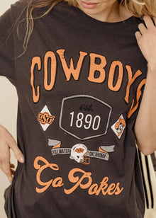  Person wearing a black t-shirt with orange and white graphics and text.