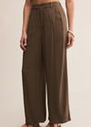 Brown wide-leg pants worn by a person on a beige background