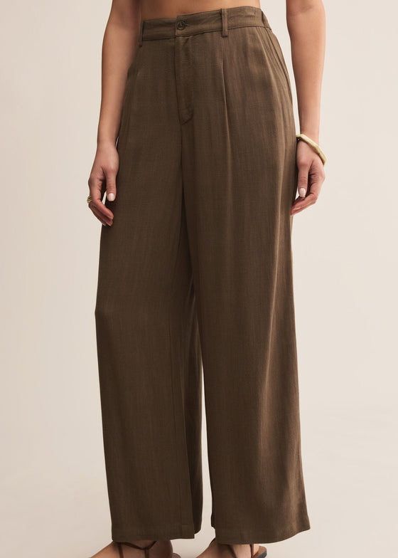 Brown wide-leg pants worn by a person on a beige background