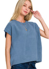 Woman wearing a dusty blue sleeveless top against a white background