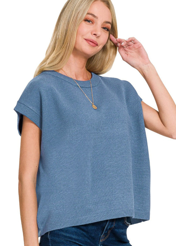Woman wearing a dusty blue sleeveless top against a white background