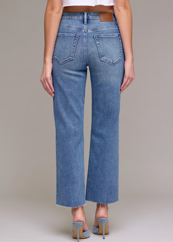 Person wearing blue jeans on a plain background
