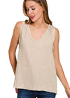 Woman wearing a beige sleeveless top with a subtle pattern on a white background