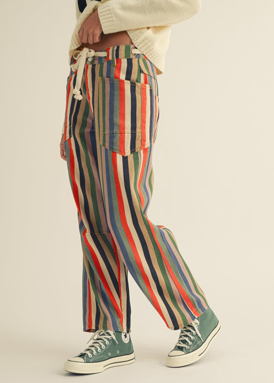 Person wearing colorful striped pants with a neutral background