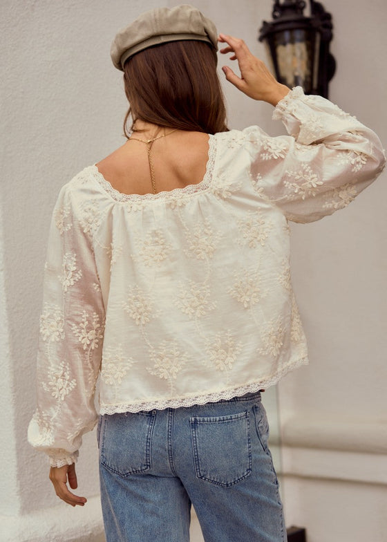 Person wearing a floral blouse and jeans with a neutral background