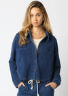 Woman wearing a blue denim jacket and matching pants on a white background