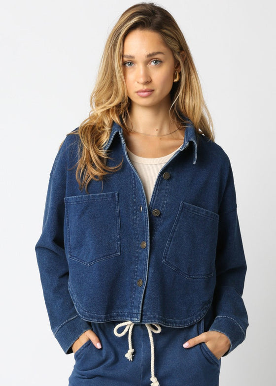 Woman wearing a blue denim jacket and matching pants on a white background