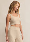 Woman wearing a beige ribbed crop top and pants against a neutral background