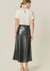 Woman wearing a white blouse and black leather skirt on a beige background