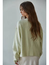 Woman wearing a light green sweater against a plain background