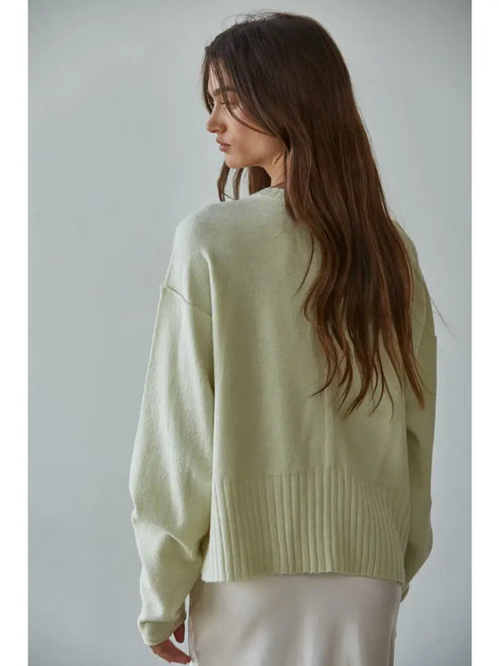 Woman wearing a light green sweater against a plain background
