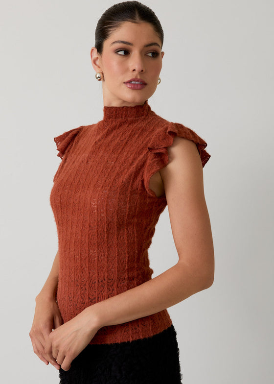 Woman wearing a rust-colored sleeveless top with ruffled shoulders against a plain background