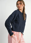Woman wearing a navy blue knitted sweater with pink pants on a white background