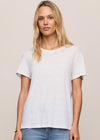 Woman wearing a plain white t-shirt and blue jeans against a beige background